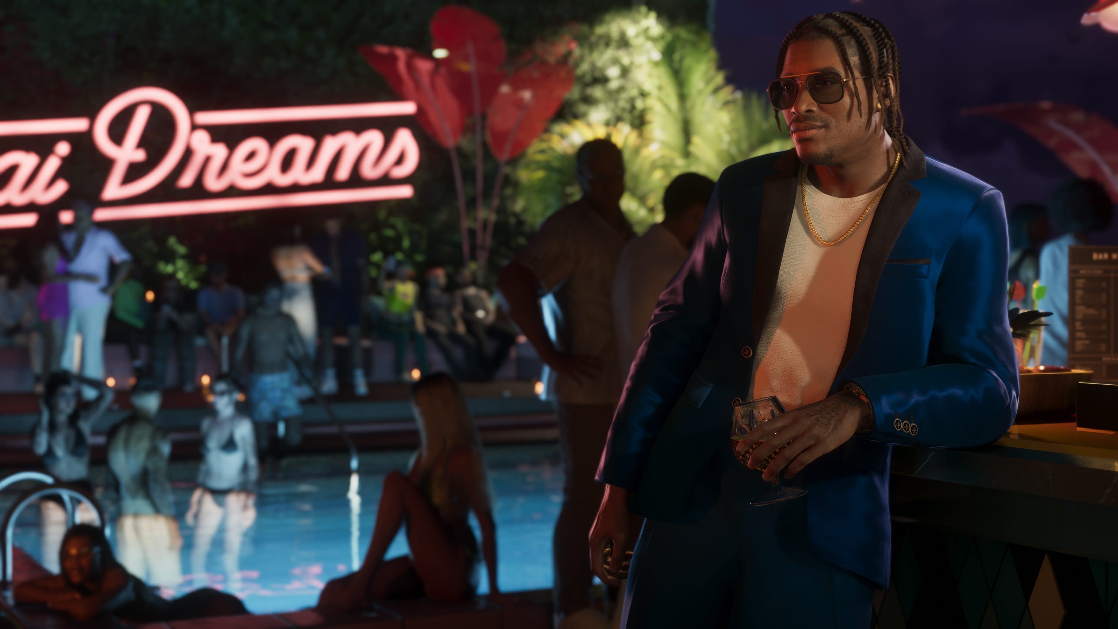 Dre’Quan Priest in a blue suit and sunglasses leans against a bar with a drink at a nighttime pool party