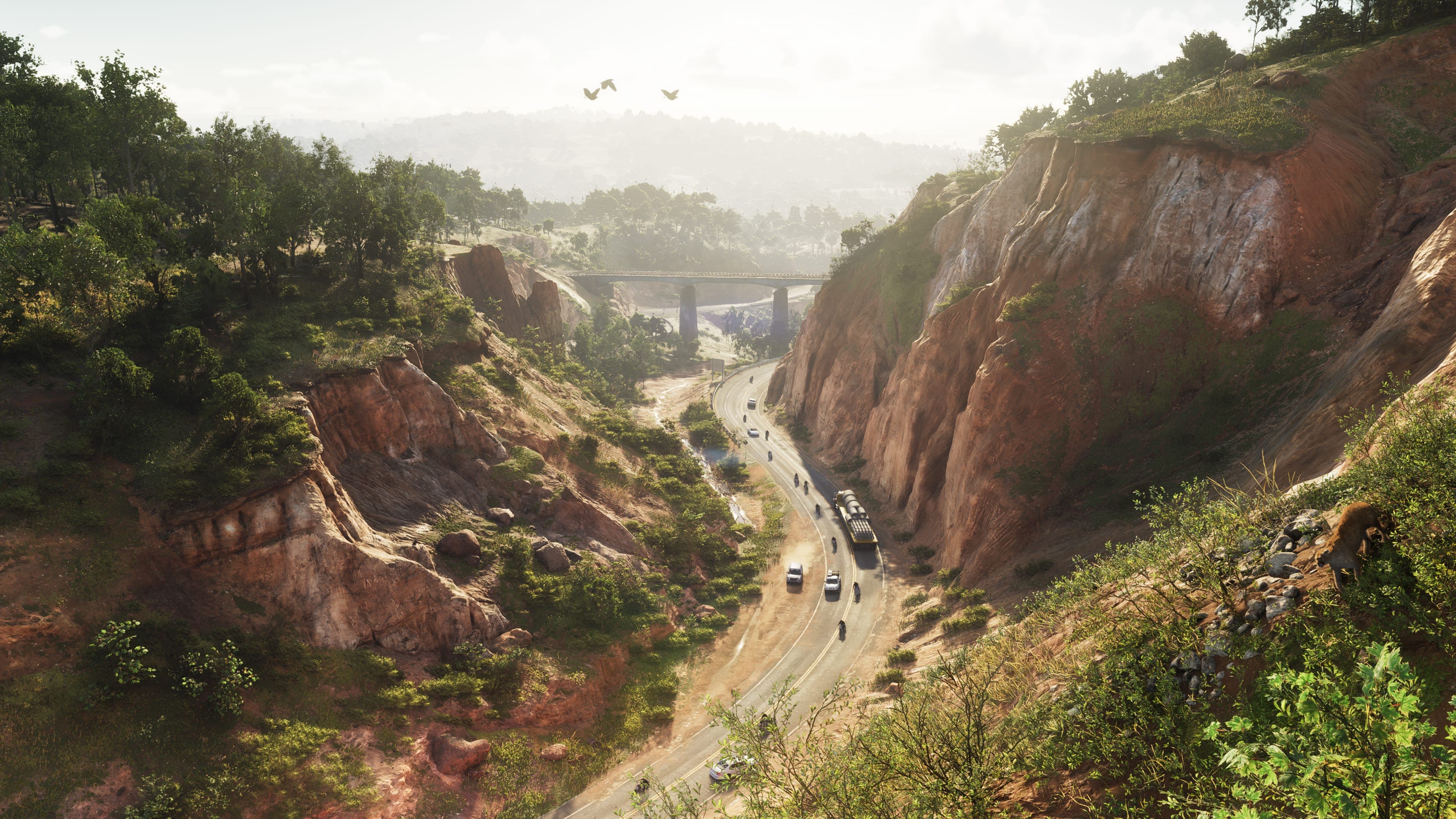 A highway winds through a canyon between steep red-earth hills topped with trees in Mount Kalaga National Park
