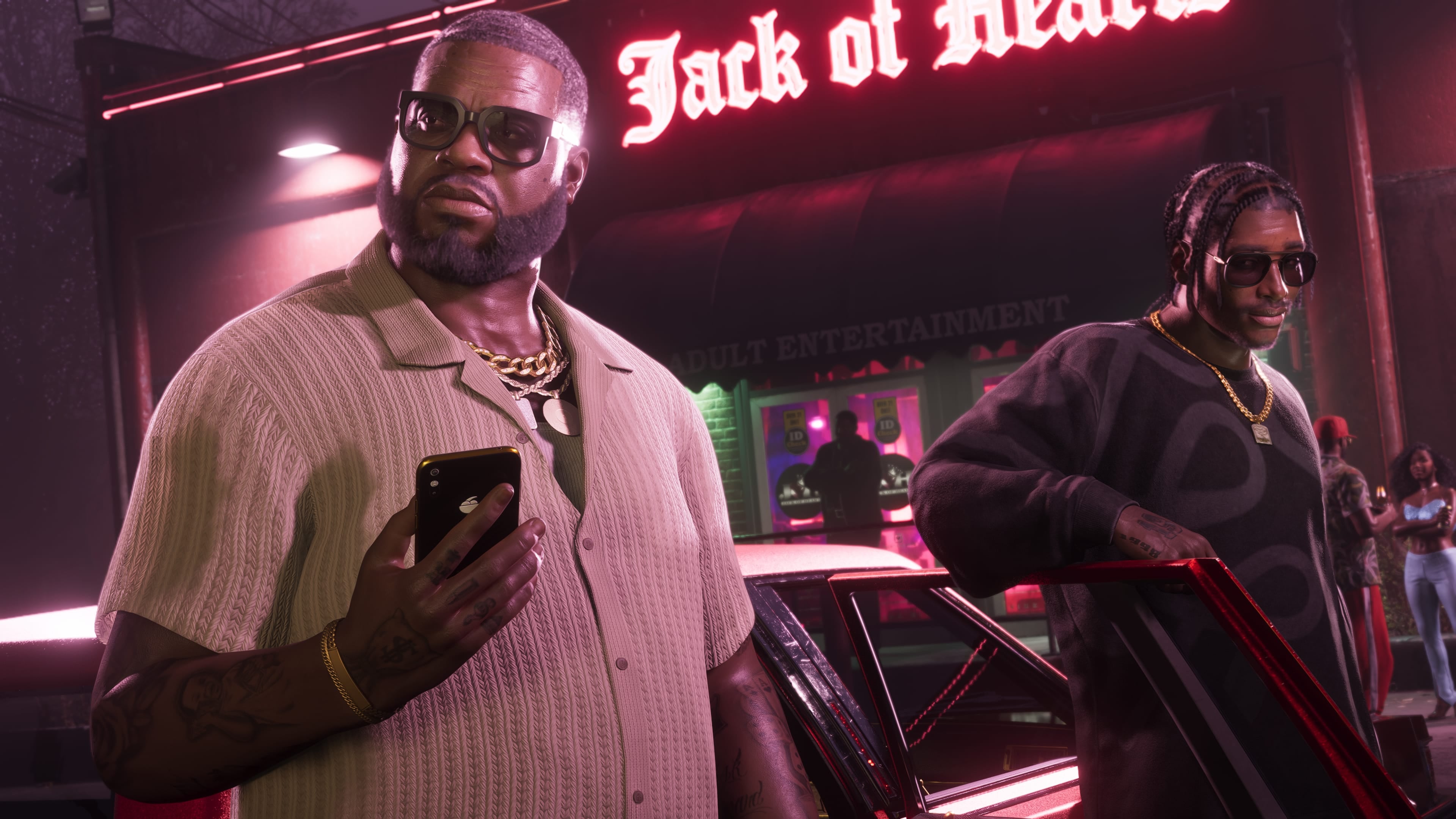 Boobie Ike and Dre'Quan Priest step out of a car beneath a Jack of Hearts neon sign in an official Rockstar screenshot.