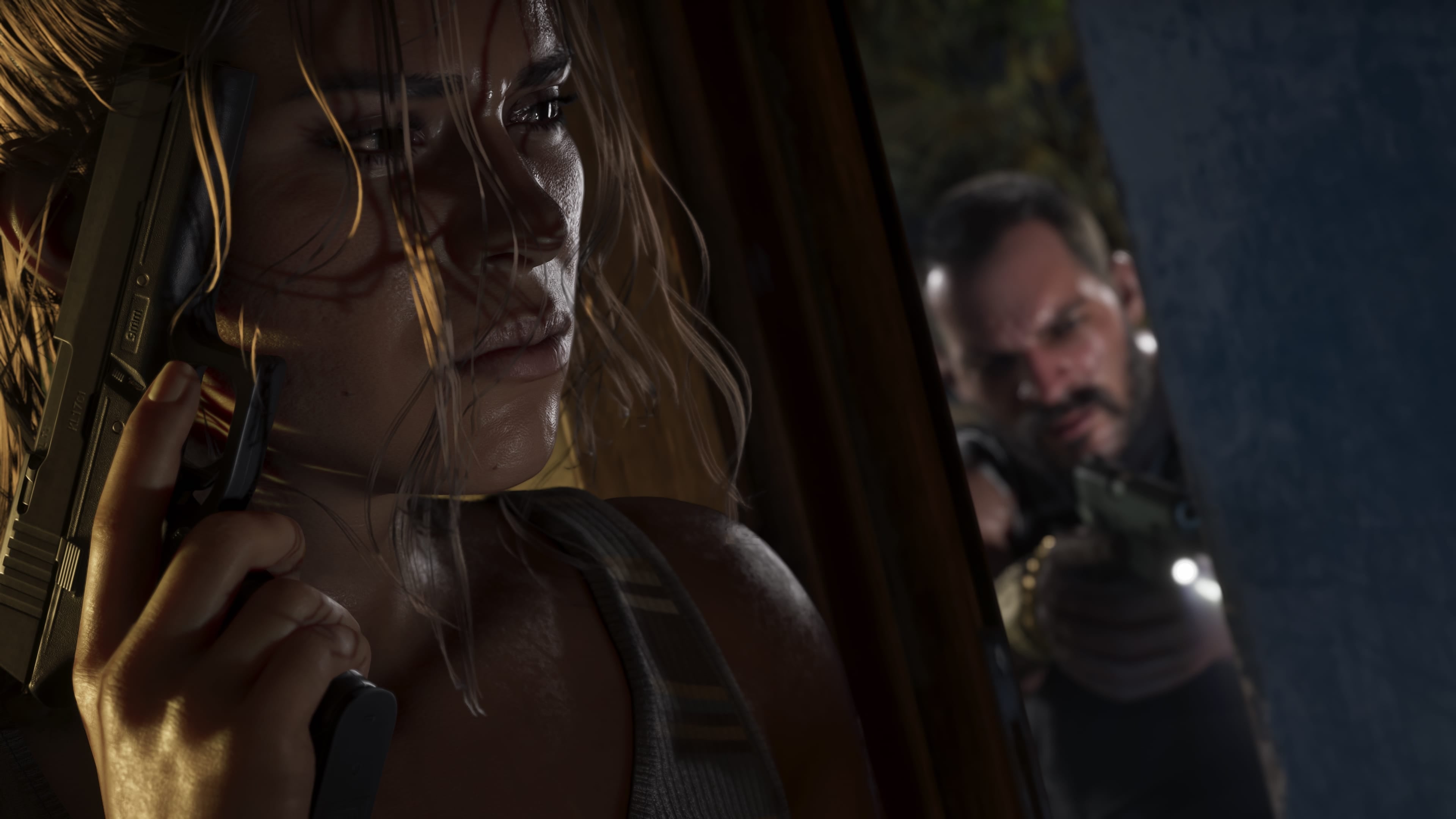 Official Rockstar GTA VI screenshot: Lucia holds a pistol beside her face, with Jason standing behind her.